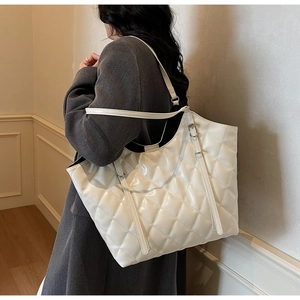 Detail of white quilted tote bag in glossy finish worn with grey casual blazer