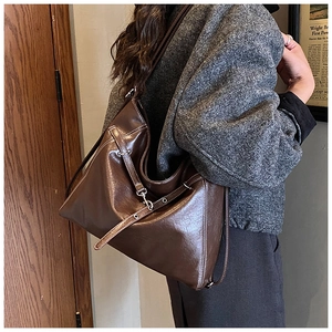 Detail view of large dark brown leather tote bag with stylish metal buckles and straps