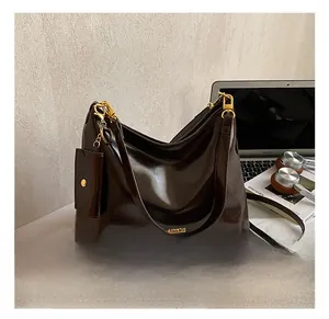 Detail of deep brown glossy leather tote with gold chain and matching mini pouch pendant