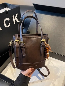 Brown PU leather bucket bag with top handles, crossbody strap and beaded charm details