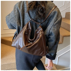 Detail of dark brown oil wax leather hobo bag with contrast stitching and metal hardware