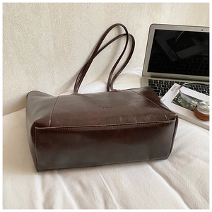 Close-up of deep brown tote bag in shiny PU leather with embossed brand logo detailing