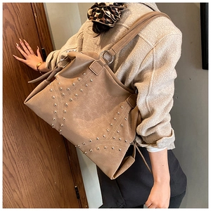 Detail of tan tote bag with silver rivet cross patterns and premium textured leather