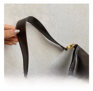Detail of a dark brown vintage tote bag featuring a wide strap and gold metal ring hook