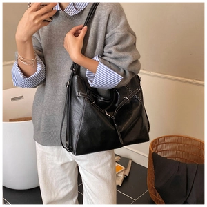 Detail of black tote bag featuring white contrast stitching and silver metal hardware