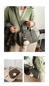Détail d'un sac à main vert foncé avec pendentif chien en peluche et bandoulière