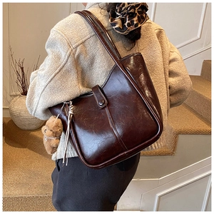 Detail of vintage brown leather tote bag with plush bear charm and long tassel accent