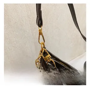 Detail of dark brown glossy leather tote featuring high-shine gold-tone lobster clasp hardware