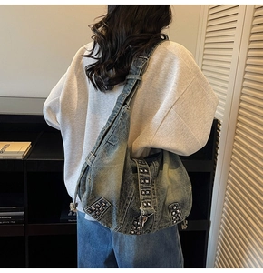 Detail of oversized washed denim tote bag featuring decorative silver square metal studs