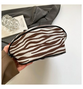 Detail der Zebra-Print-Textur und schwarzer Lederpaspel an der halbmondförmigen Tasche