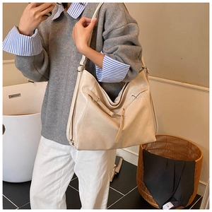Close-up of cream faux leather tote bag showing grainy texture and silver metal buckle