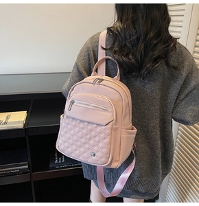 Dettaglio di uno zaino rosa in ecopelle con tasca trapuntata a rombi e tasche laterali