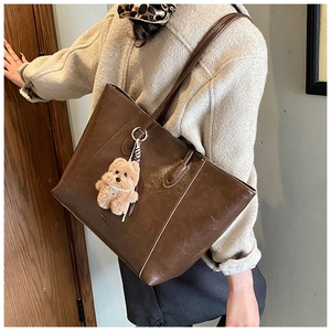 Detail of vintage brown tote bag with smooth wax finish and cute plush puppy pendant