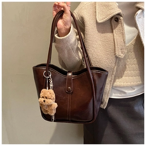 Detail of vintage brown leather tote bag with a cute plush bear charm on the handle