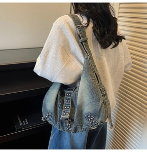 Detail of washed denim hobo bag with vintage metal studs and adjustable shoulder strap