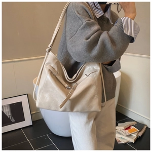 Detail of off-white large capacity tote bag with smooth faux leather texture and strap