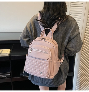 Vista dettagliata di uno zaino rosa in ecopelle trapuntata indossato da una modella nello studio