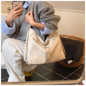 Detailed view of cream hobo shoulder bag with silver buckles on a casual outfit