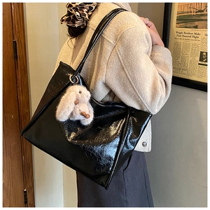 Detail der glänzenden schwarzen Tote Bag mit Plüschhasen-Anhänger und Goldringen