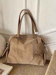 Vintage brown tote bag with silver studs and metal ring handles on a woven mat