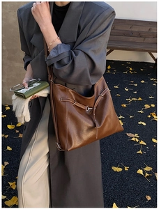 Detail of vintage brown leather tote bag with white stitching and metal buckle accents
