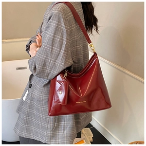 Detail einer glänzenden tiefroten Ledertasche mit kleinem Umschlag-Beutel-Zubehör