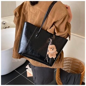 Close-up of black PU leather tote bag with SHENGMEI embossed text and bear pendant
