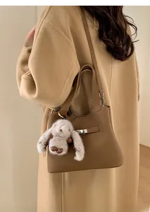 Detail of dark brown lychee leather bucket bag with silver twist lock and plush bunny charm