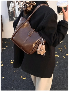 Detailed view of brown oil-wax leather tote bag with a cute plush bear charm on the strap