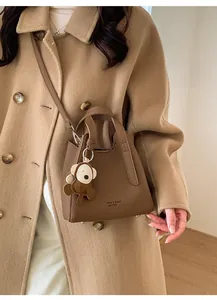 Brown leather bucket bag with cute monkey charm shown on khaki wool coat style