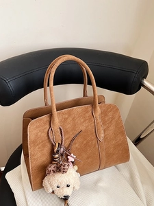 Sac à main marron minimaliste avec texture mate et breloque chien en peluche décorative