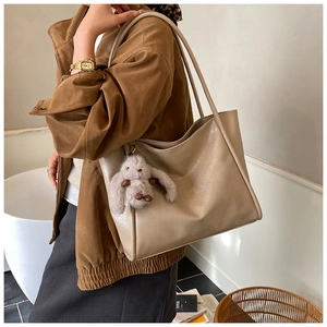 Detail einer hellbraunen Shopper-Tasche mit grauem Plüschhasen-Anhänger am Henkel