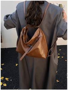 Close-up of vintage brown leather backpack featuring white stitching and metal eyelet detail