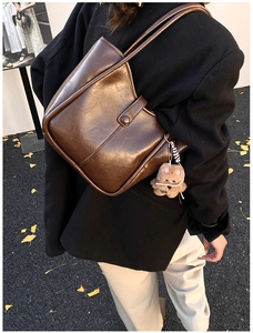 Close-up of brown vintage tote bag with thin straps and a cute brown plush bear charm