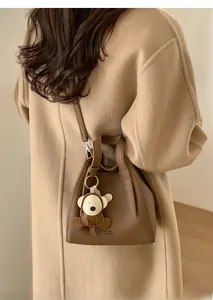 Detail of vintage brown leather bucket bag with monkey charm and embossed brand logo