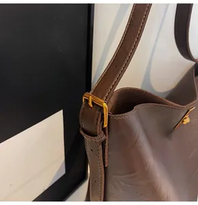 Detailed macro view of dark brown pebbled leather texture with golden metal buckle on hobo bag