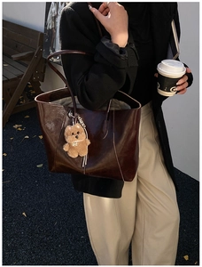 Retro dark brown oily leather tote bag with plush puppy charm on a street style shoot