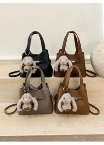 Detail view of lychee leather bucket bags in four colors with plush rabbit charms