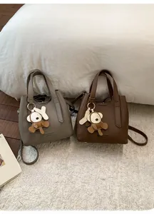 Detail view of mini bucket bags in gray and brown leather with cute bear charms