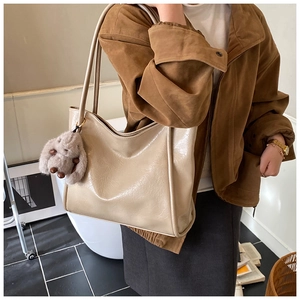 Detailansicht einer beigen großen Shopper-Tasche mit flauschigem Hasenanhänger am Model
