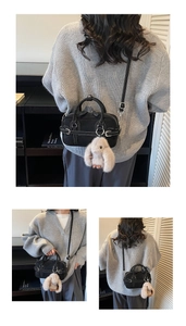 Détail d'un sac cylindre en toile noire avec coutures blanches et breloque lapin