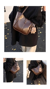 Detail of vintage brown leather tote bag with vertical stitching and plush bear charm