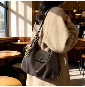 Detailed view of retro large capacity brown leather tote with a cute bear keychain accessory