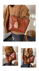 Detail of vintage brown leather tote bag with vertical stitching and cute bear charm