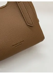 Close-up of brown litchi pattern PU leather texture with neat stitching and logo