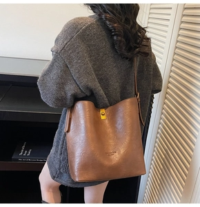 Detailed view of brown bucket bag with a gold twist lock and a textured finish