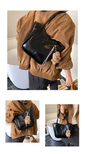 Detail of minimalist black shiny tote bag featuring a cute plush bear charm accessory