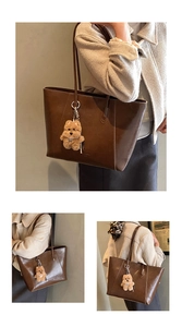 Detail view of large brown vintage tote bag with cute plush bear charm and long shoulder strap