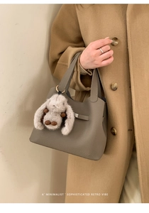 Détail du sac seau taupe avec texture grainée et charmant pendentif lapin en peluche