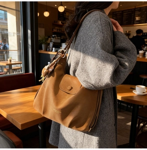 Detail of vintage brown leather tote bag with plush bear charm and magnetic flap closure
